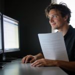 The Silent Bottleneck: Why Hardware Choice Defines Developer Workflow Efficiency A developer looking at dual monitors in a workspace setting.